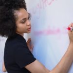 Une femme écrit sur un tableau blanc