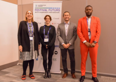 4 speakers standing in front of International Cooperation Futures Festival pullup banner